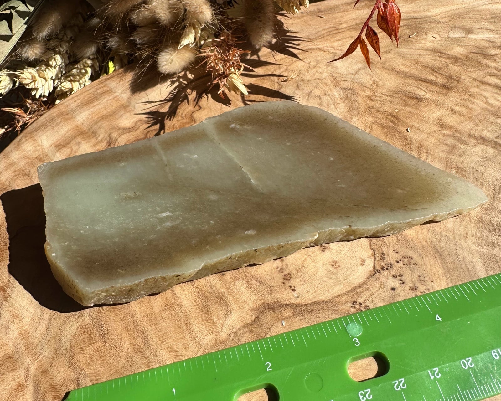 Siberian rough jade 225 grams on a wooden surface beside a green ruler