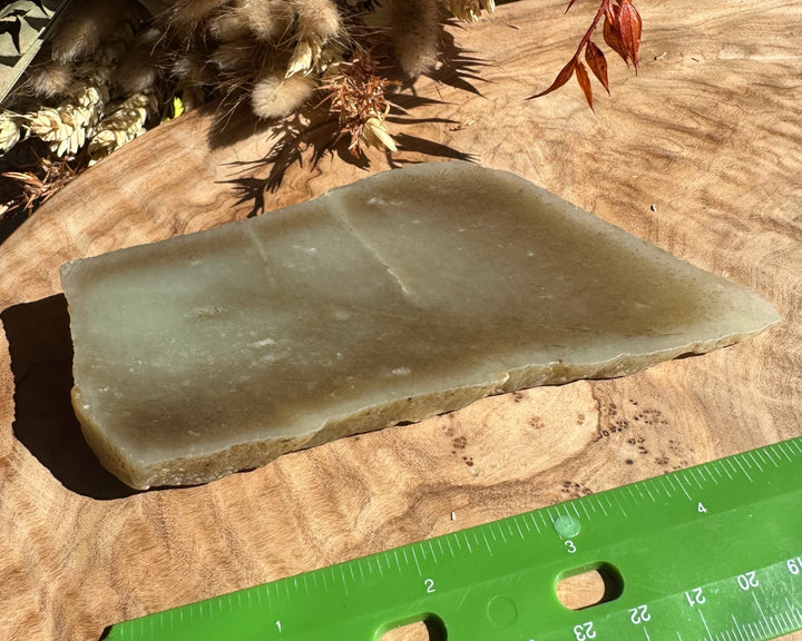 Siberian rough jade 225 grams on a wooden surface beside a green ruler
