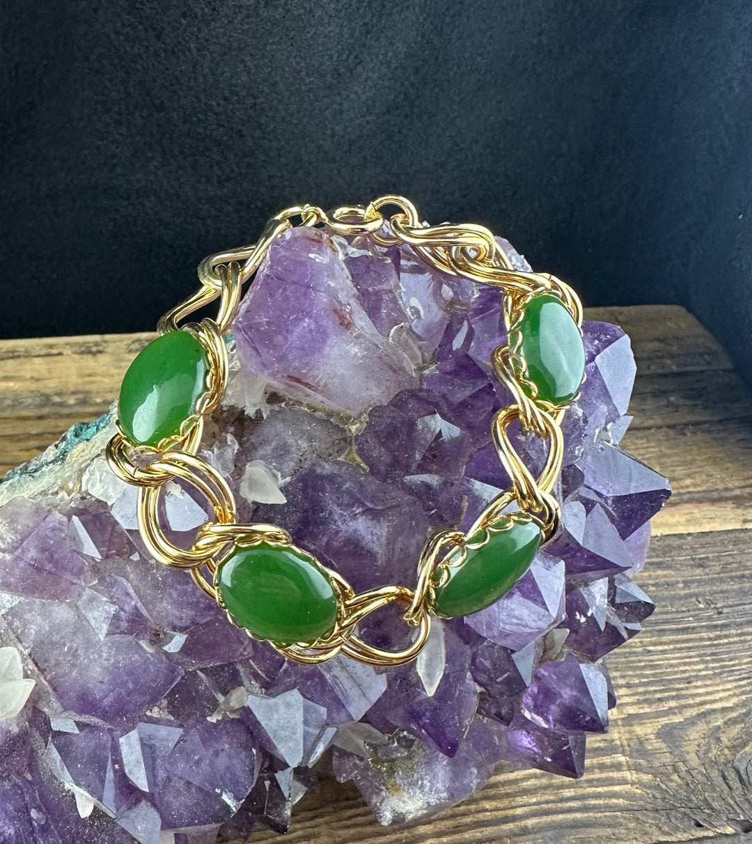 Vintage jade bracelet arranged on a purple amethyst cluster with gold twisted links.