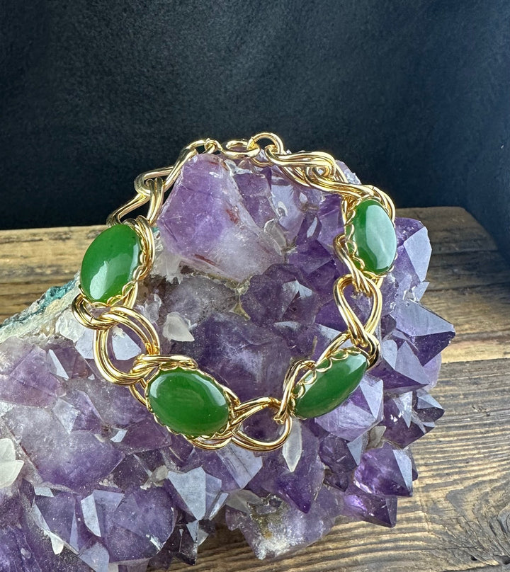 Vintage jade bracelet arranged on a purple amethyst cluster with gold twisted links.