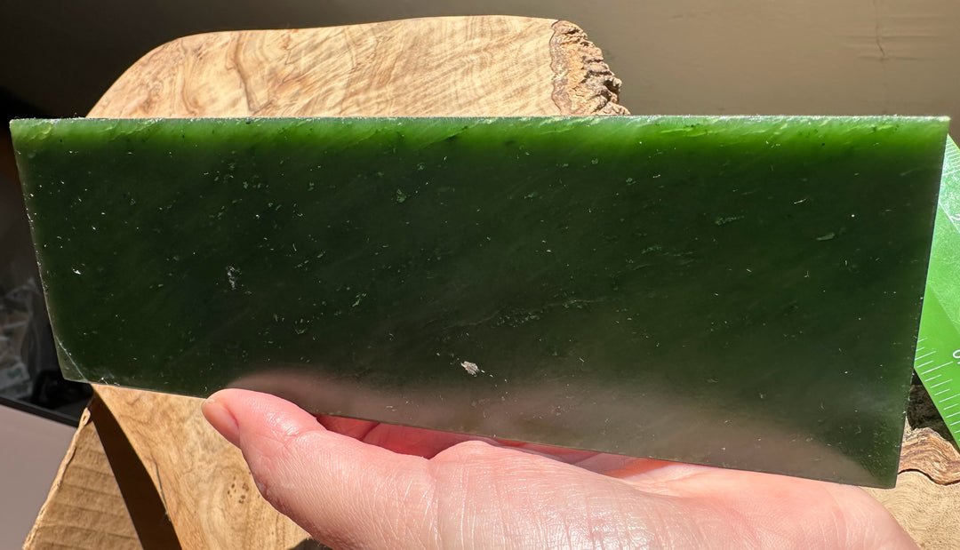Canadian jade slab in bright green held outdoors with hand and blue sky in the background