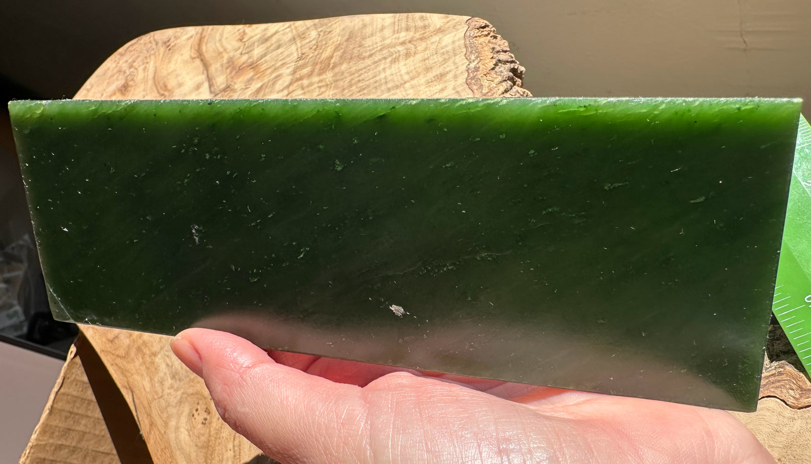 Canadian jade slab in bright green held outdoors with hand and blue sky in the background