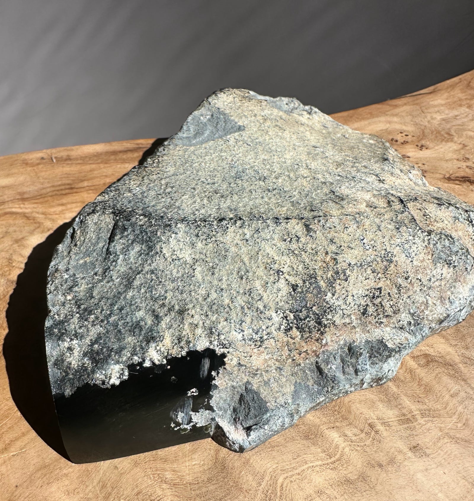 Wyoming meteorite specimen weighing 1.4 lb with rough gray fusion crust on a wooden surface