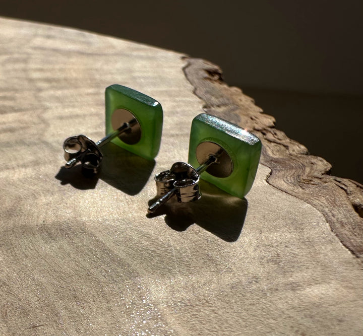 Back view of jade square 8mm stud earrings with metal posts and butterfly backs on a wooden surface