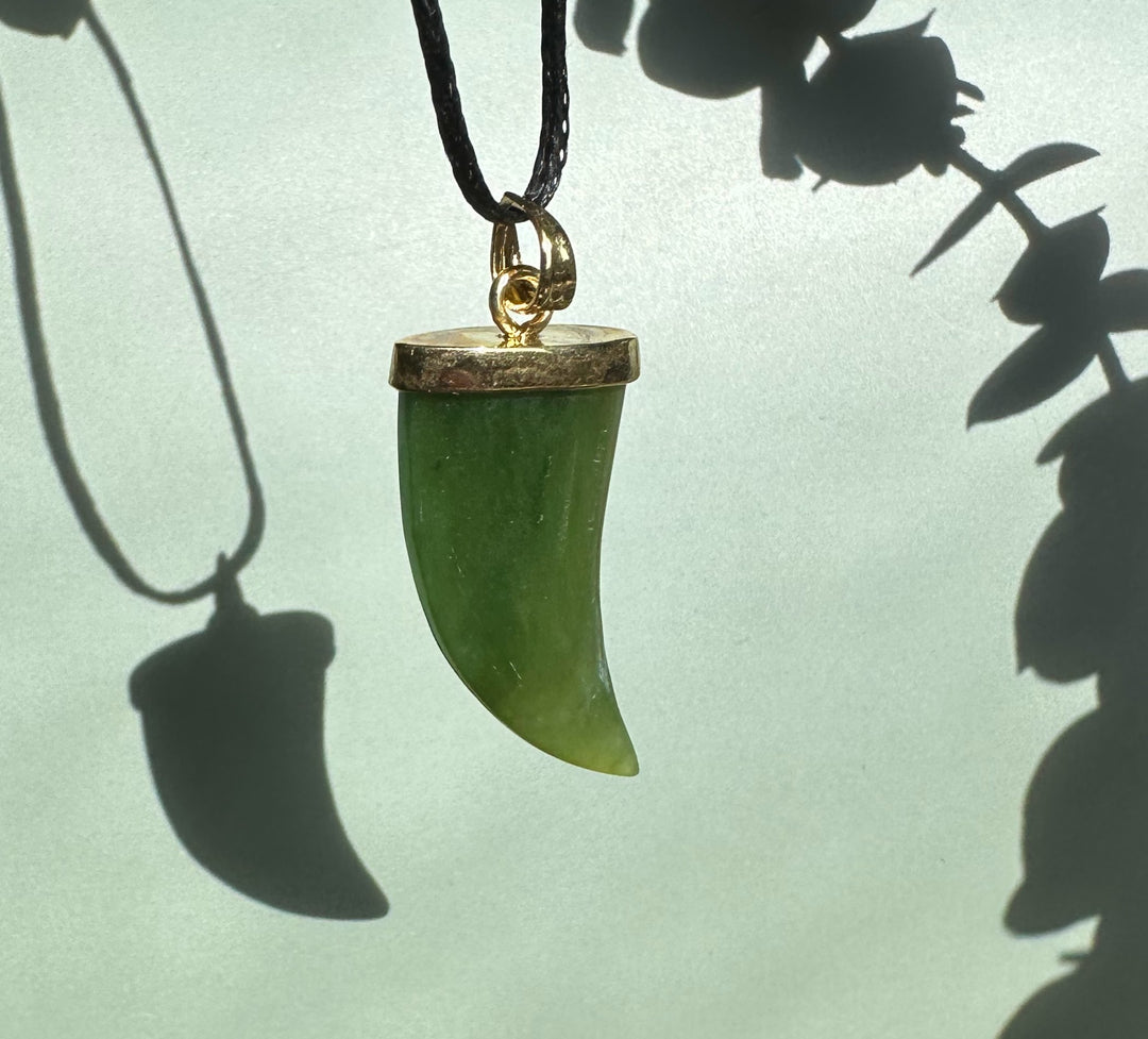 Green jade bear claw pendant with gold cap on a black cord