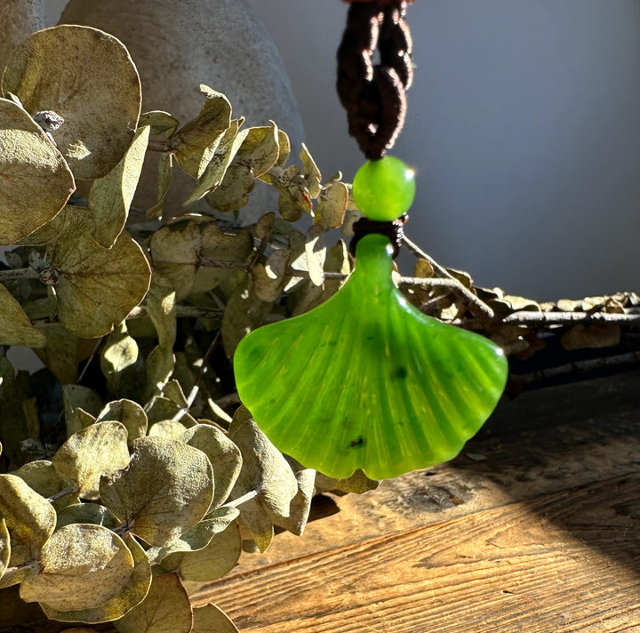 Close-up of the Canadian Jade Ginkgo Leaf Pendant glowing in sunlight showing vivid green leaf on a brown cord