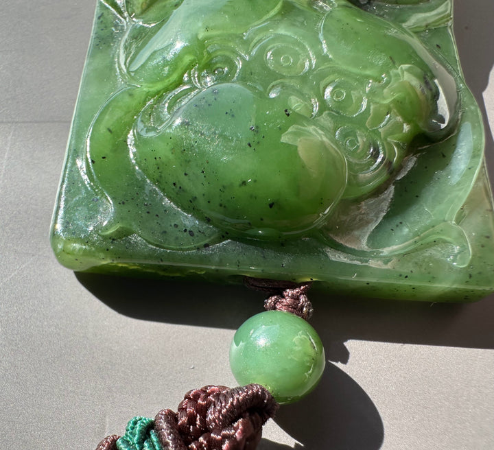 Large green jade lotus pendant carved on a square block with a brown cord and green bead
