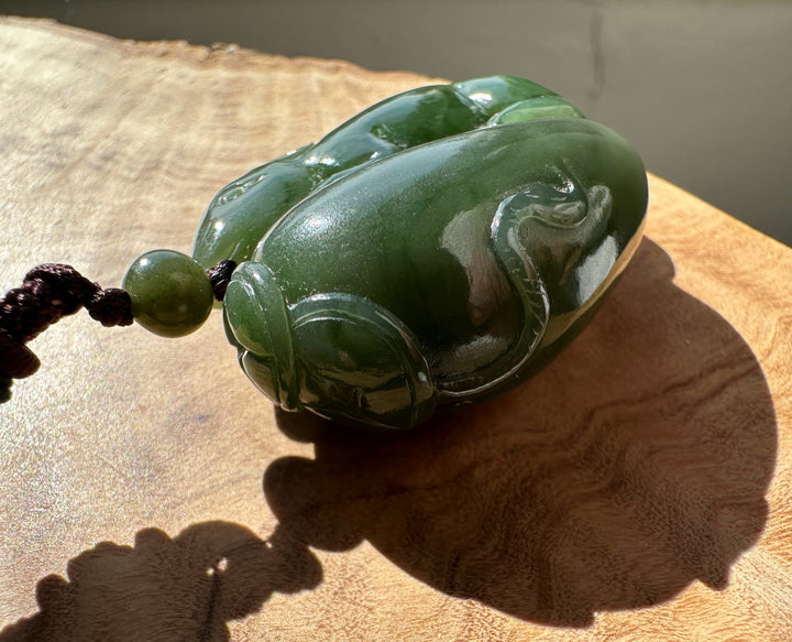 Green jade pendant on a wooden surface