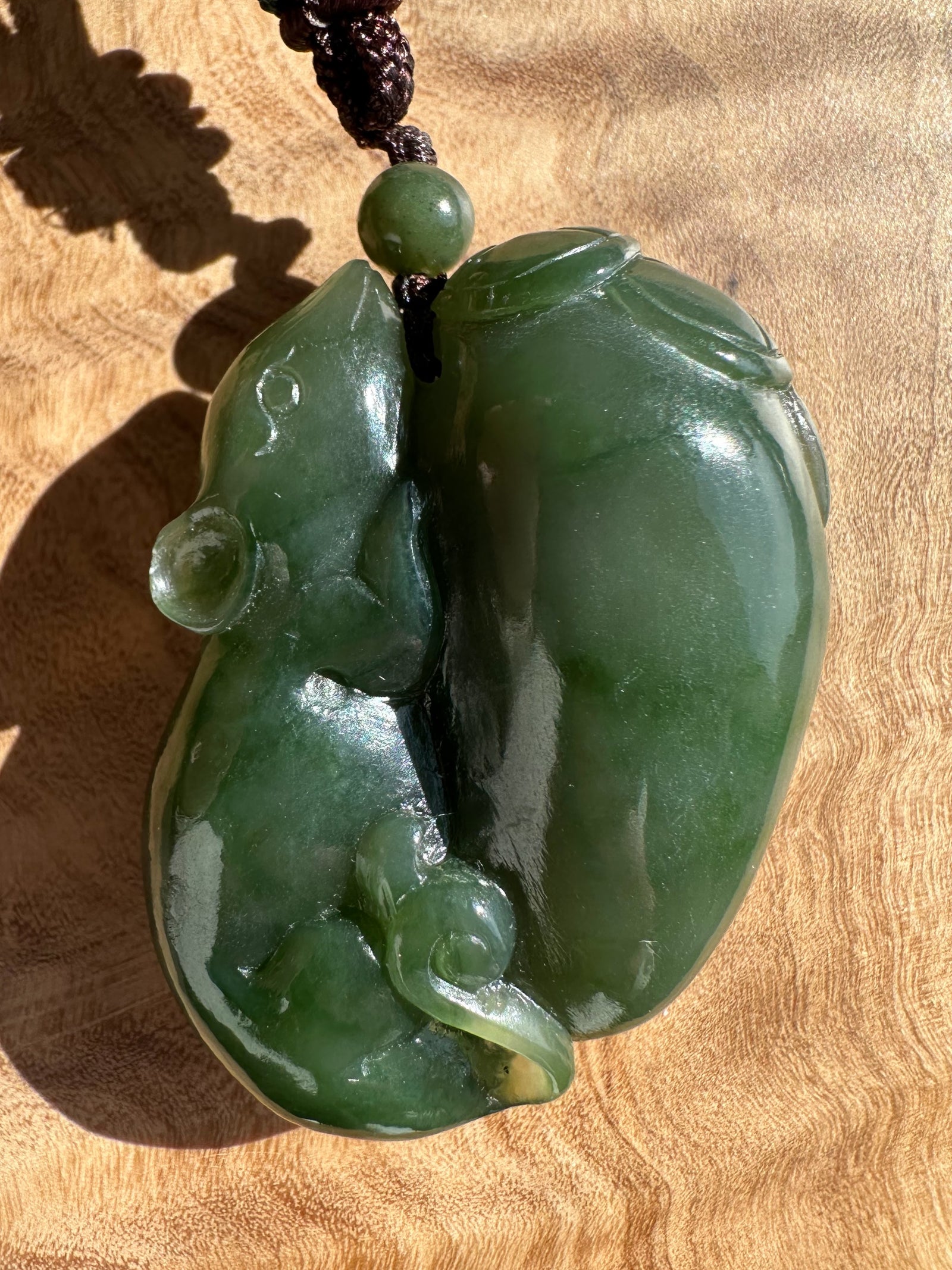 Green jade pendant on a wooden surface