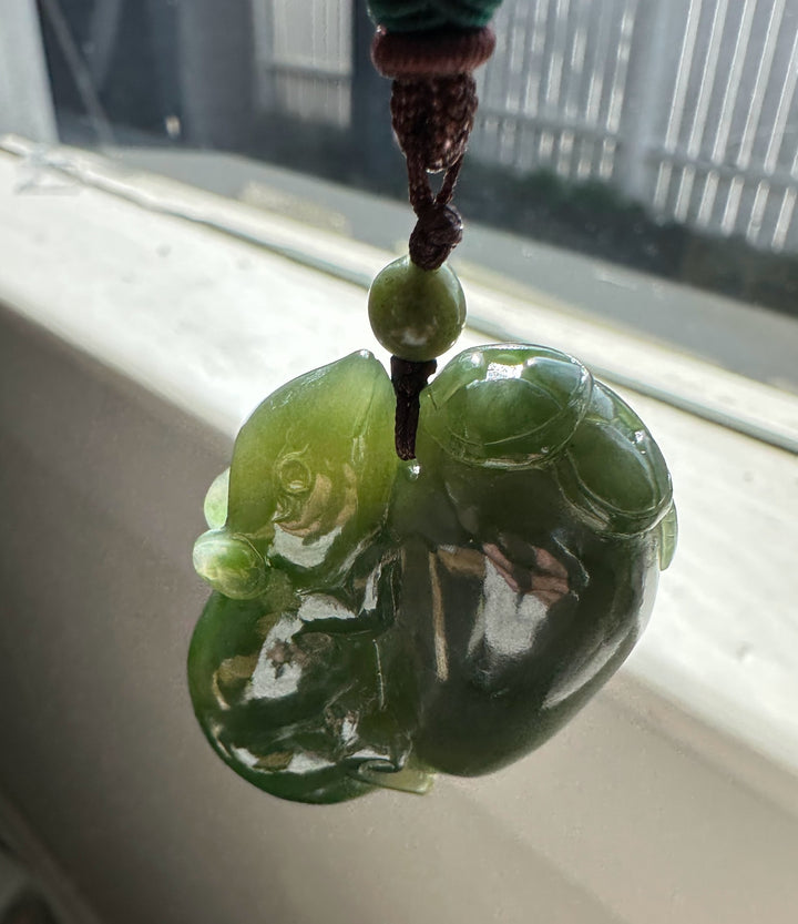 Green jade pendant hanging from a cord with a blurred background