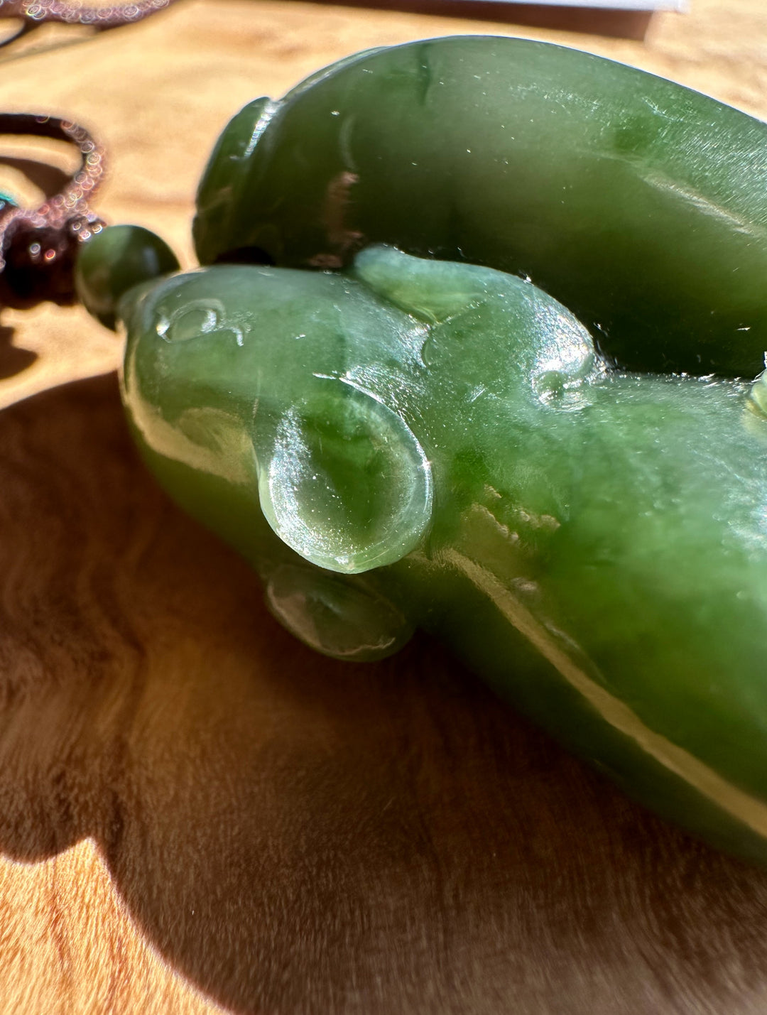 Green jade pendant on a wooden surface