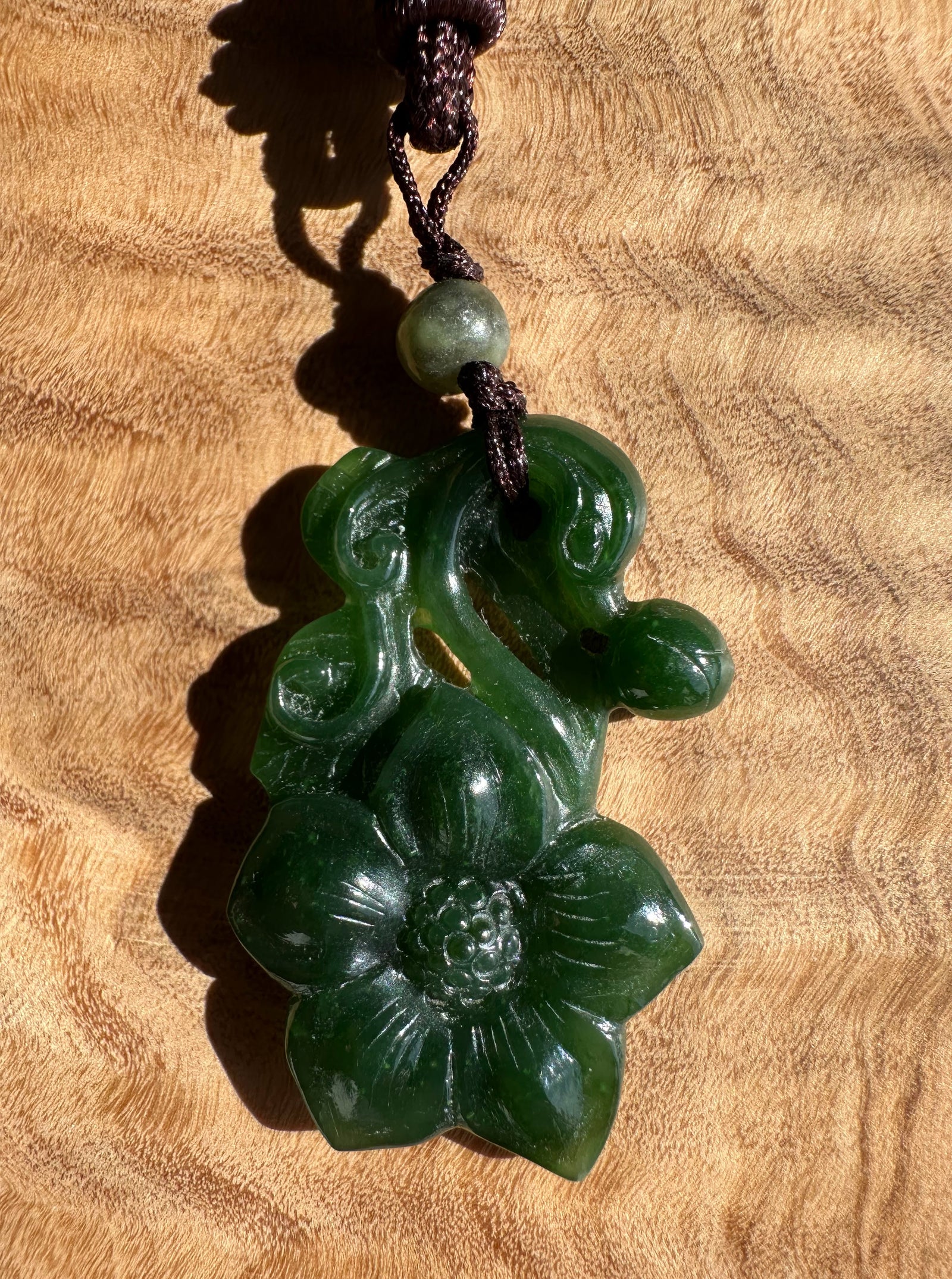 Green jade pendant on a wooden surface