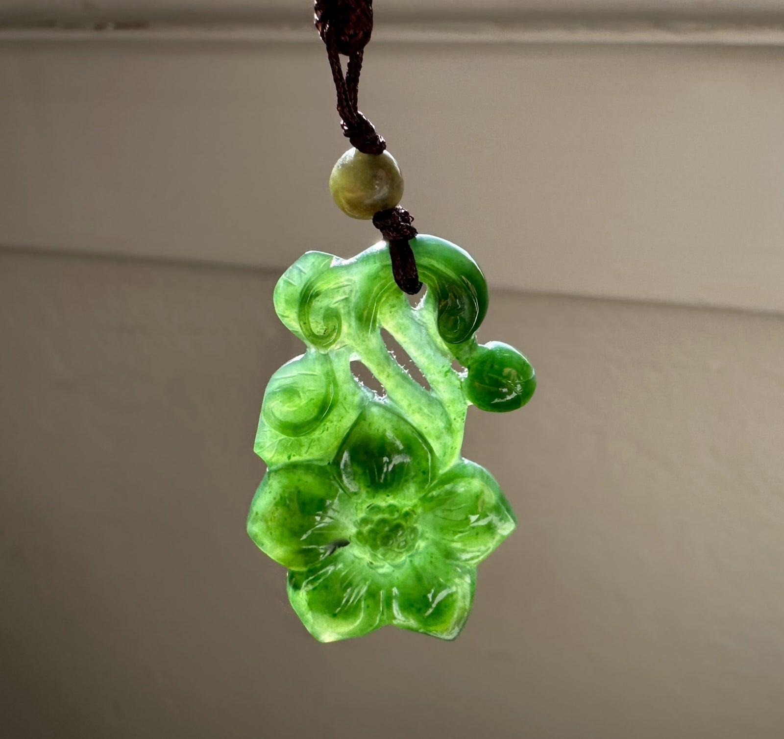 Green jade pendant on a plain background