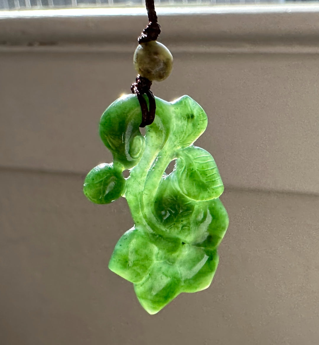 Green jade pendant on a plain background