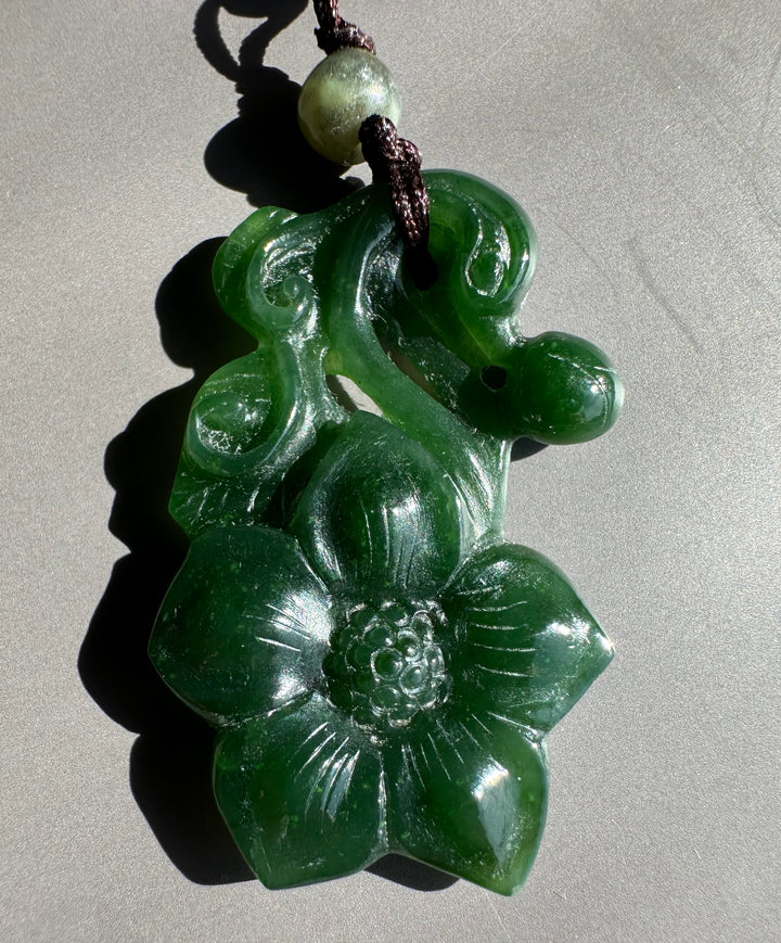Dark Green jade flower pendant on a grey background