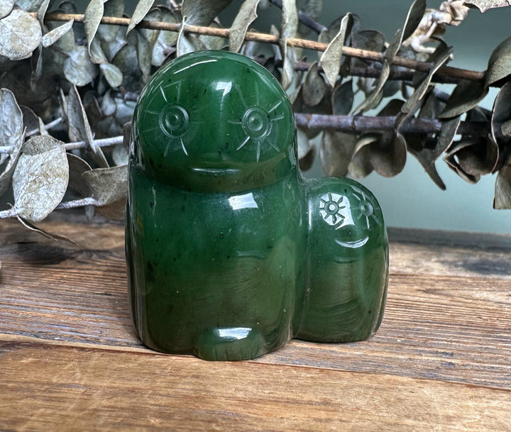 Canadian Jade Owl and Owlet carved from dark green jade resting on a wooden surface