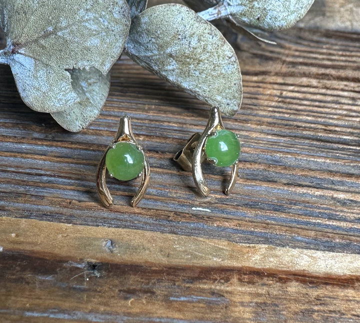 Vintage Jade Wishbone Earrings with green jade cabochons in gold curved frames resting on a rustic wooden surface.