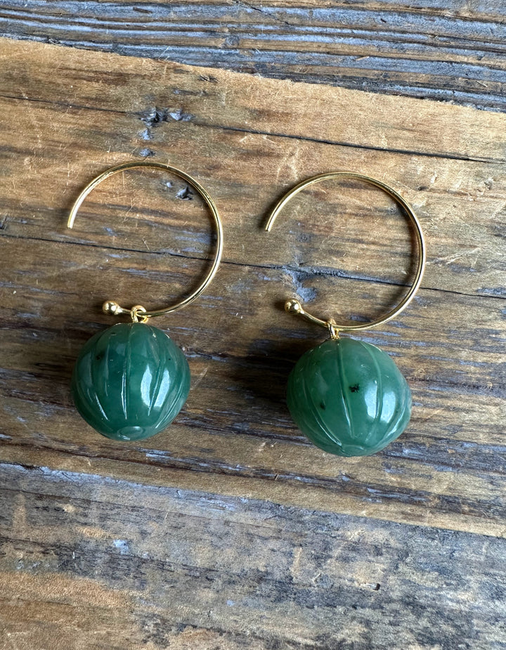 Pair of Canadian Jade Drop Bead Earrings in gold hoops on a rustic wooden surface.