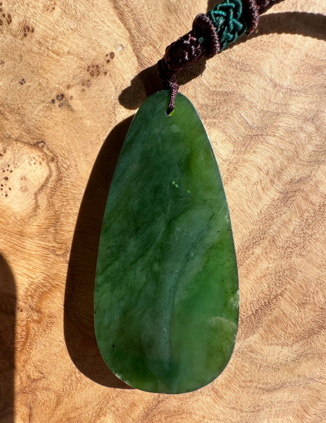 Green jade pendant on a wooden surface