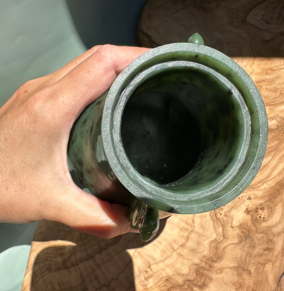 Hand holds Canadian River Jade Vase from above with glittery rim and mottled green glaze.
