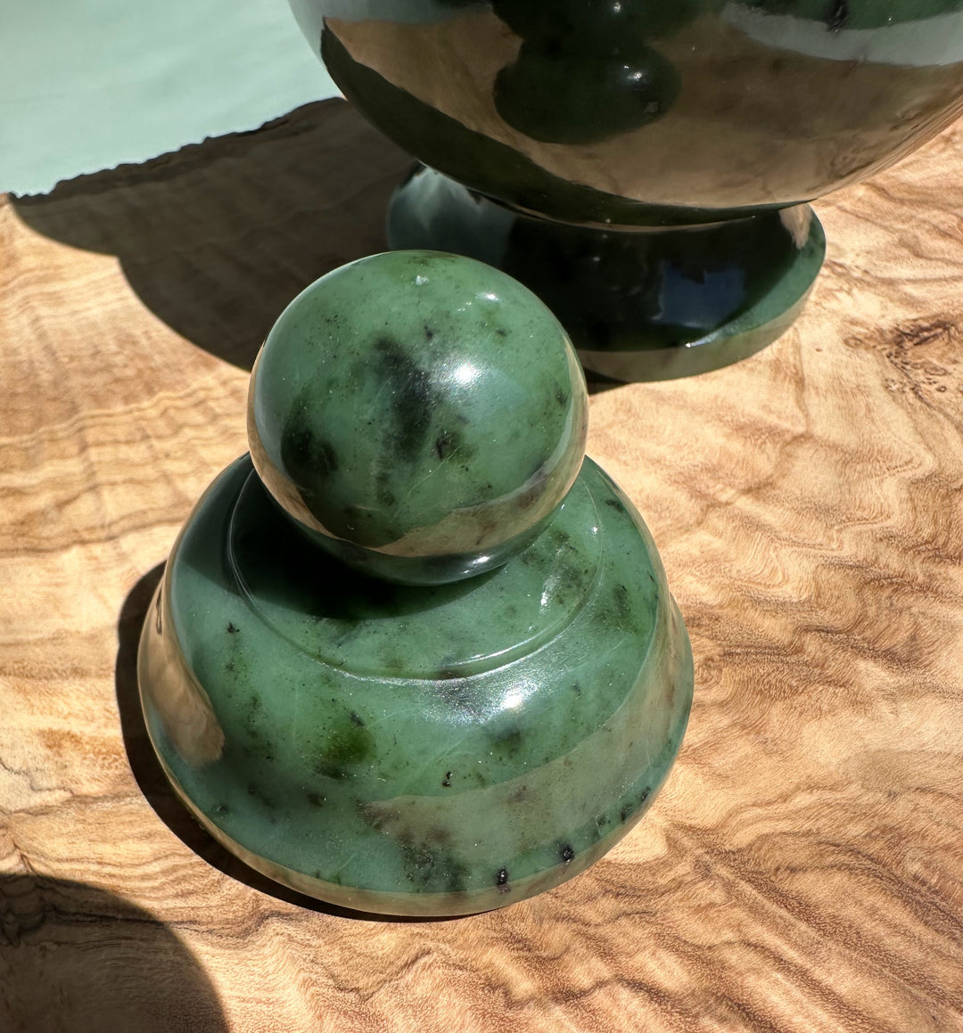 Close-up view of the jade vase showing base and spherical lid with green mottled stone on wood