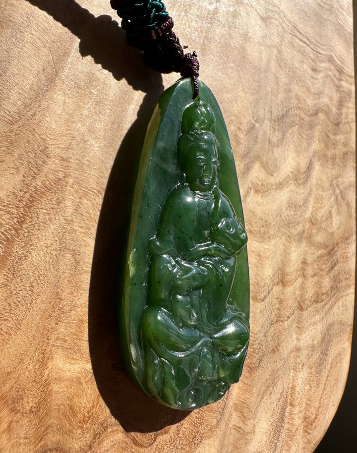 Green jade pendant with a figure on a wooden surface