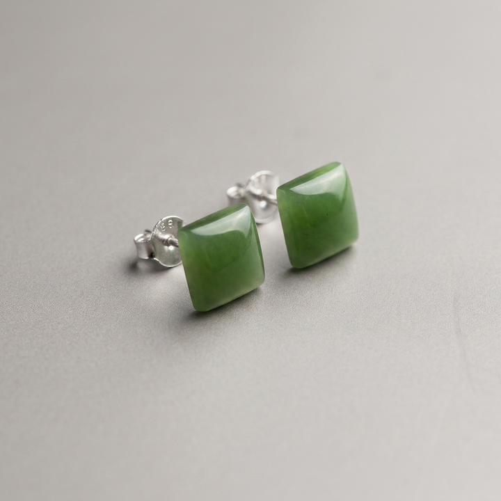 Green jade square stud earrings with silver posts on a neutral gray background.
