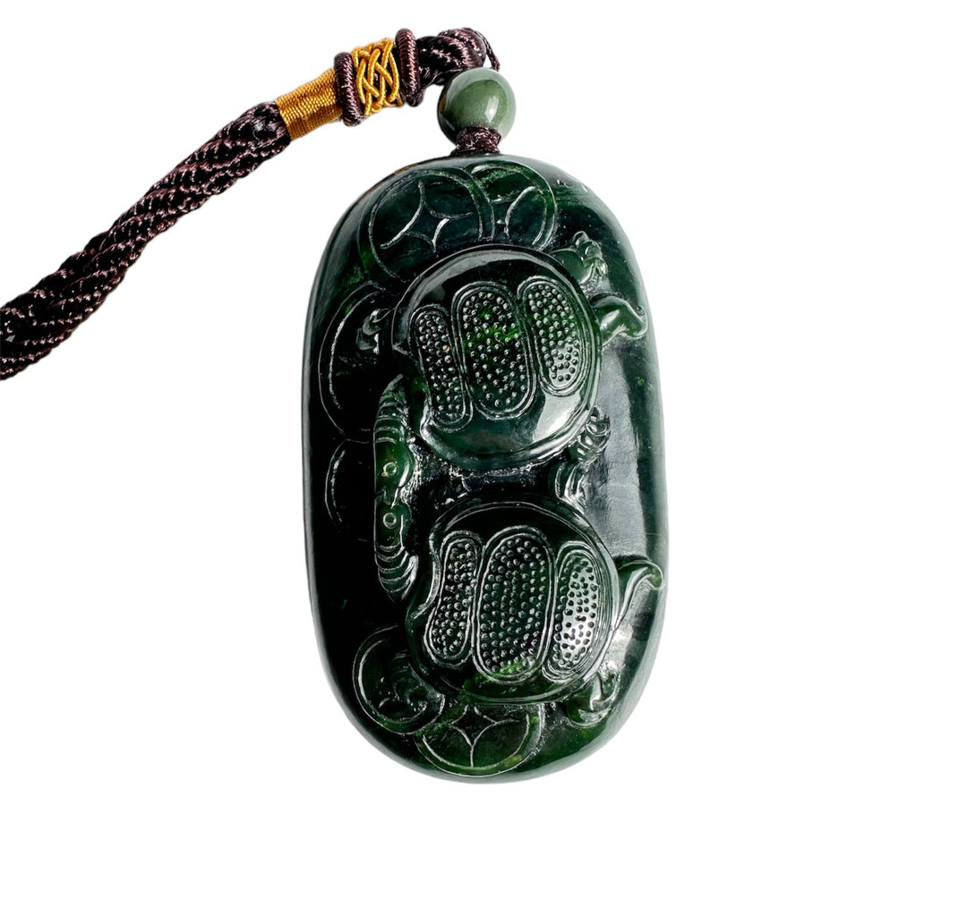 Dark green jade pendant carved with two turtles on a braided cord necklace
