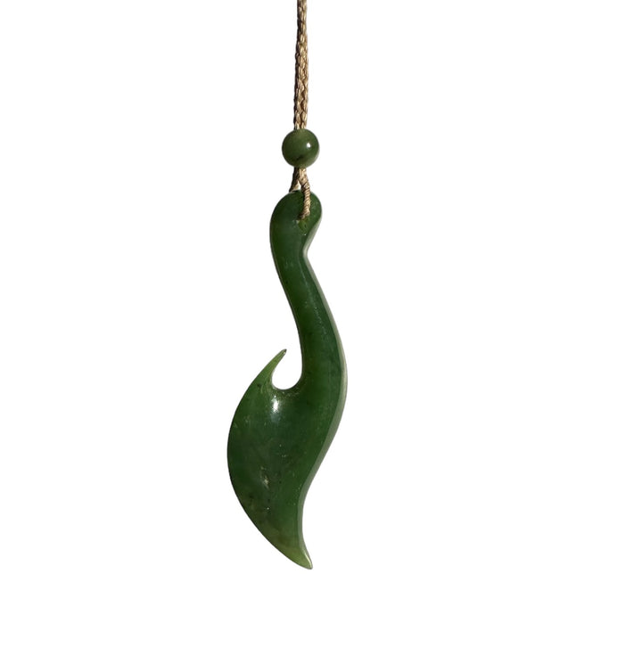 Jade fish hook pendant suspended from a brown cord with a bead, shown against a white background