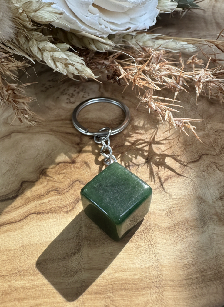Green keychain on a wooden surface with flowers in the background