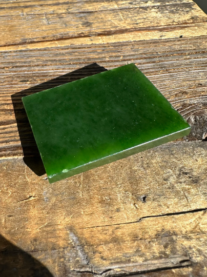 A+ Siberian nephrite jade slab resting on a weathered wooden surface