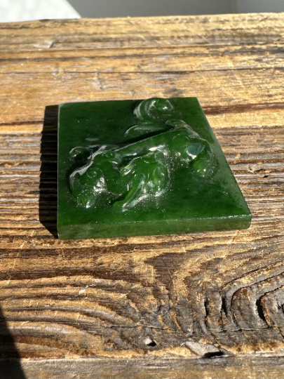 Green A+ Siberian nephrite jade block with an intricate carved scene on its top surface.