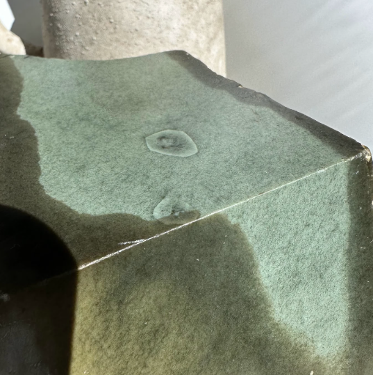 Close up of a green Wyoming Sage mineral block with a pale circular feature on top.