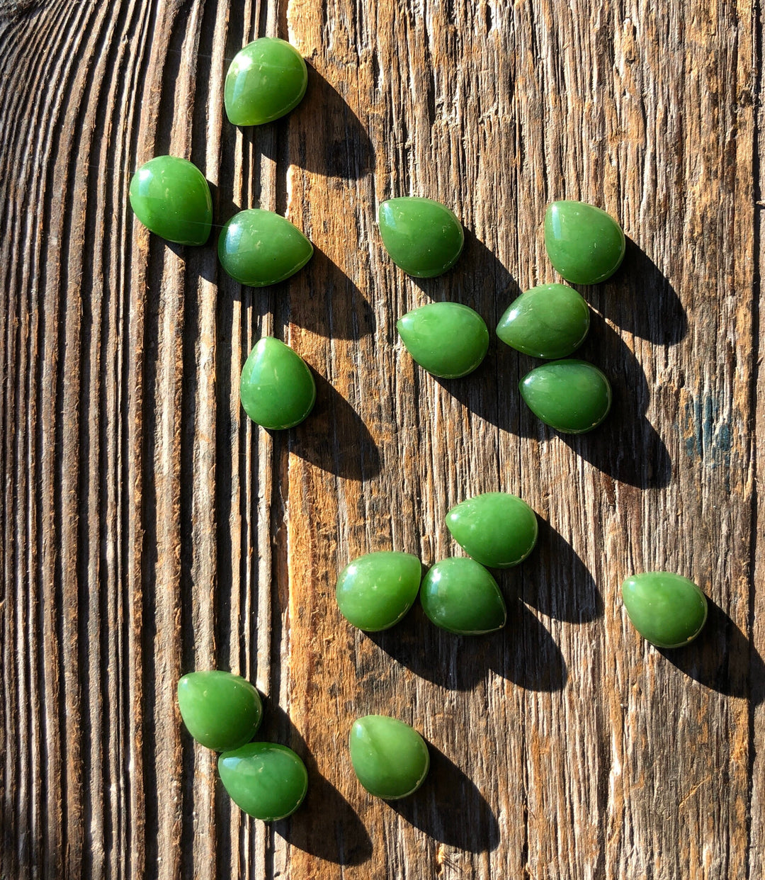 Green pear shaped cabochons on a rustic wooden surface