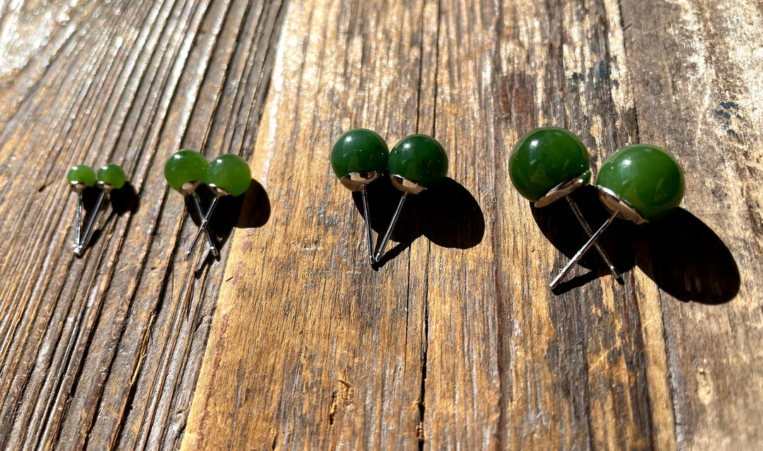 Three sizes of green round bead stud earrings displayed on a wooden surface