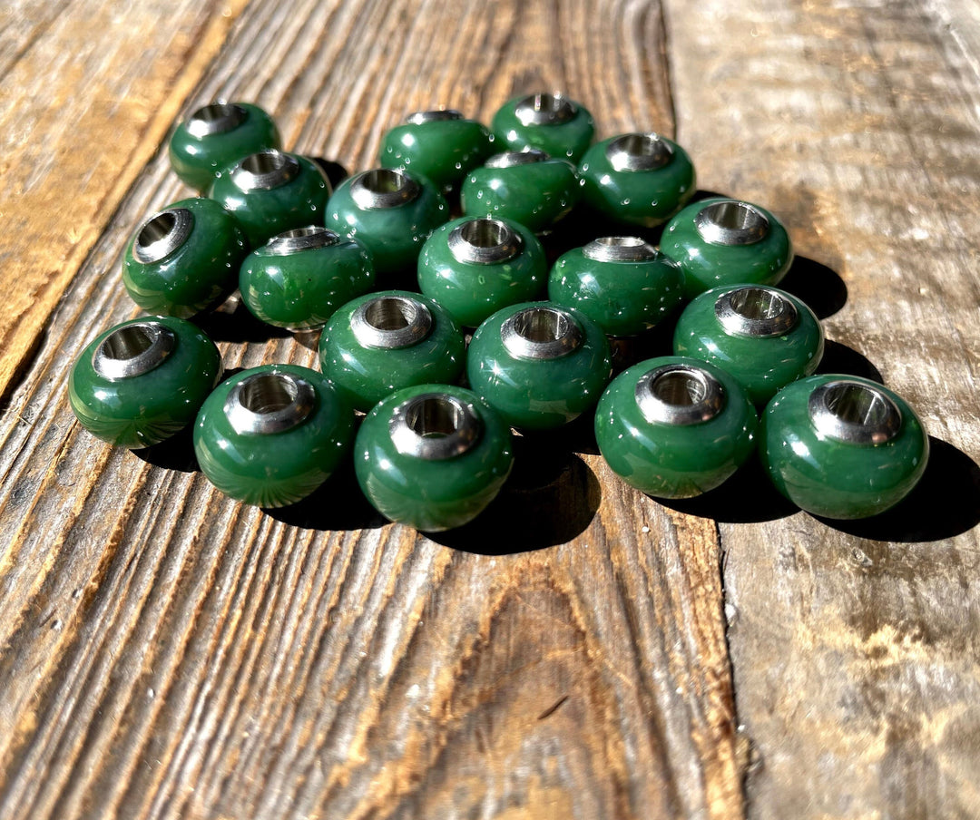 Group of green jade beads with metal cores laid on a rustic wooden surface