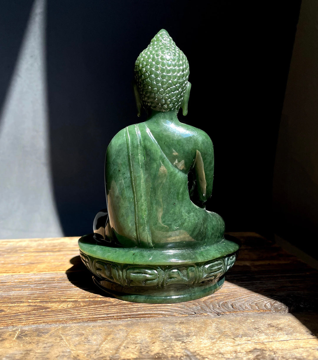 Back three-quarter view of green nephrite jade Buddha on a carved base