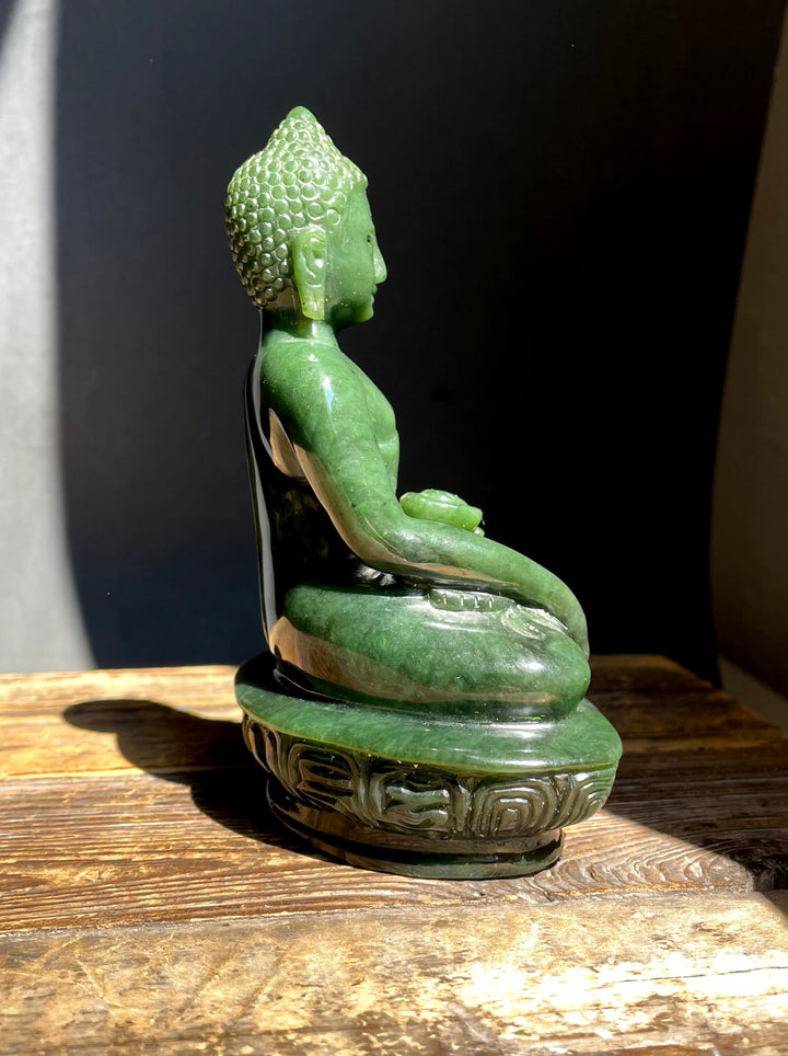 Back view of a green nephrite jade Buddha with curled hair and draped robe