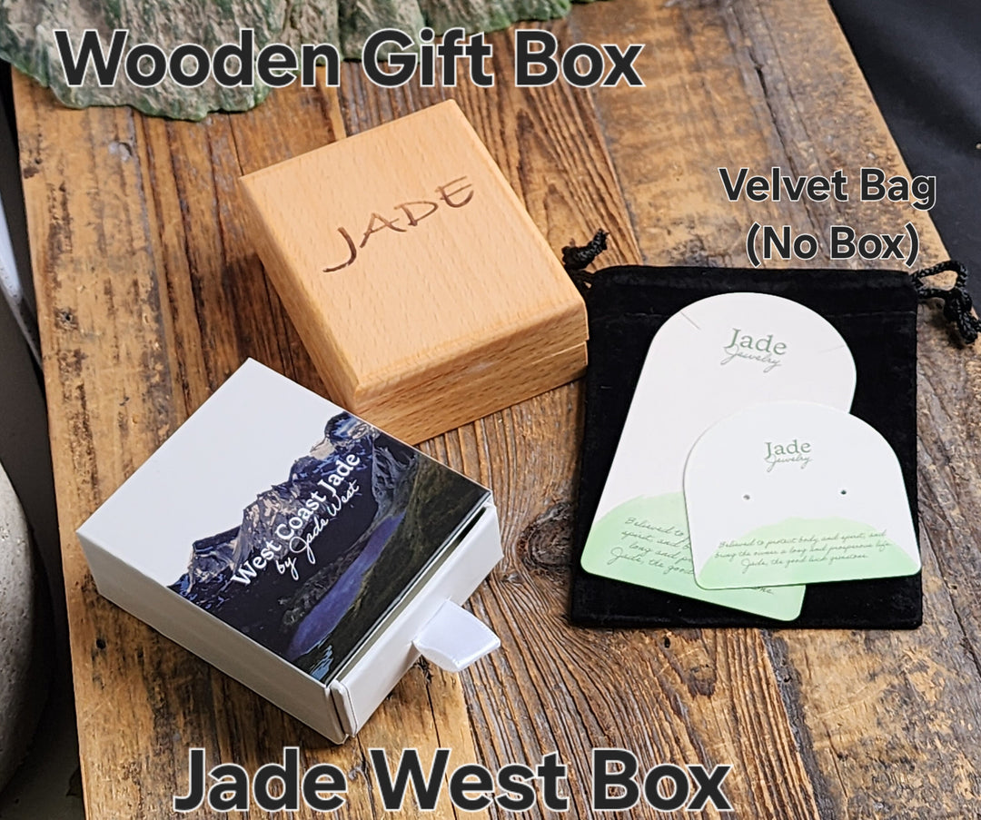 Wooden gift box and velvet pouch packaging for Jade West jewelry displayed on a rustic wooden surface.