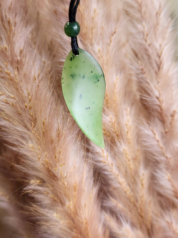 Green jade leaf pendant on a black cord with a small green bead above