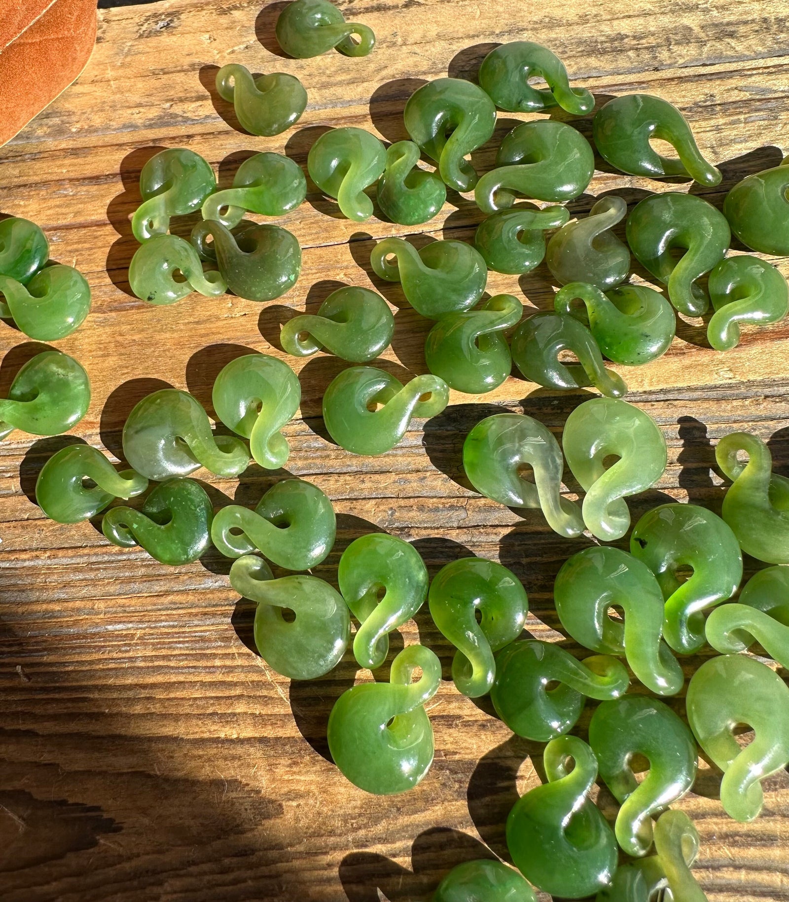 Canadian Jade Infinity Twist beads scattered on a wooden surface