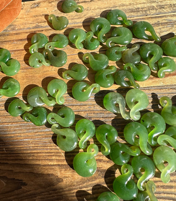 Canadian Jade Infinity Twist beads scattered on a wooden surface
