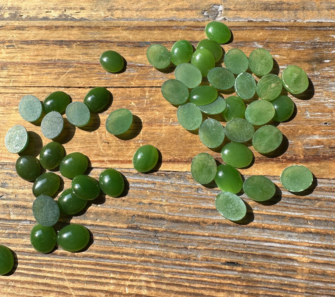 Assorted green jade discs scattered on a wooden surface.