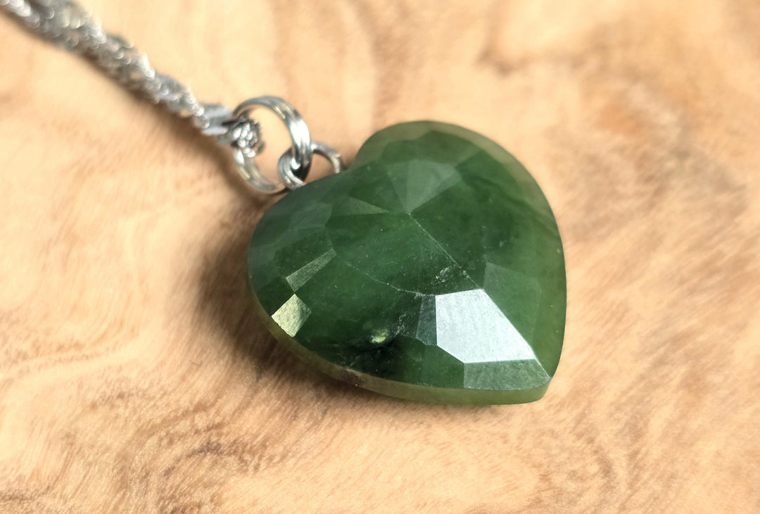 Faceted deep green nephrite jade heart pendant on a silver chain.
