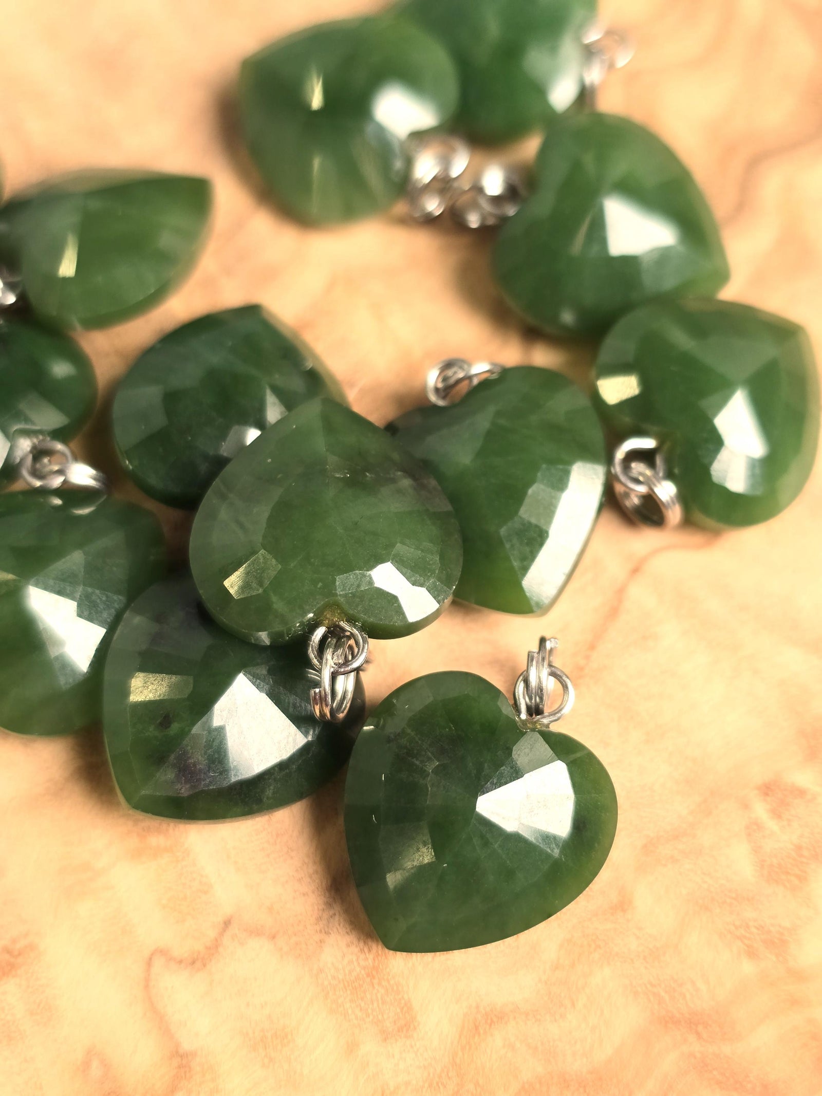 Group of 16mm green nephrite jade faceted heart pendants with silver loops.