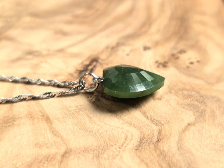 Close-up of a 16mm green nephrite jade faceted heart pendant on a silver chain.