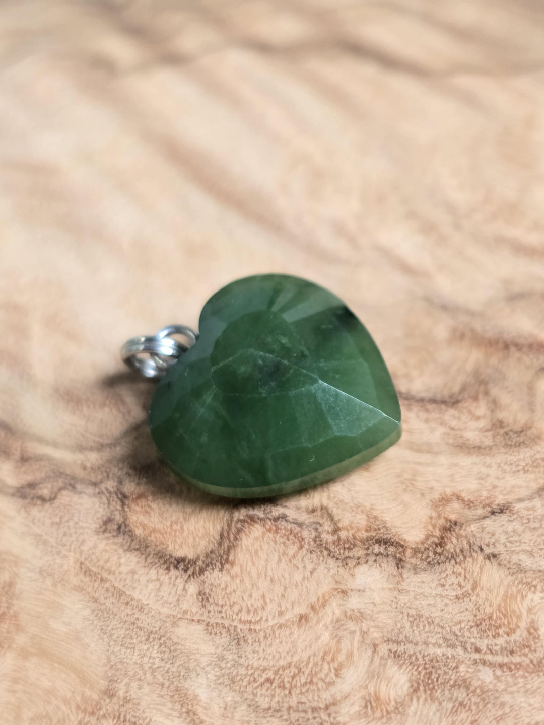 Green nephrite jade heart pendant with faceted surface and silver bail