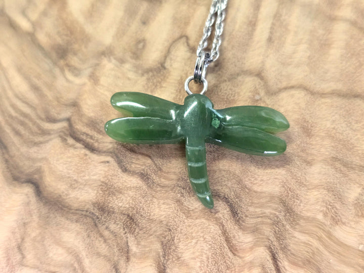 Close up of green jade dragonfly pendant with a silver bail on a chain