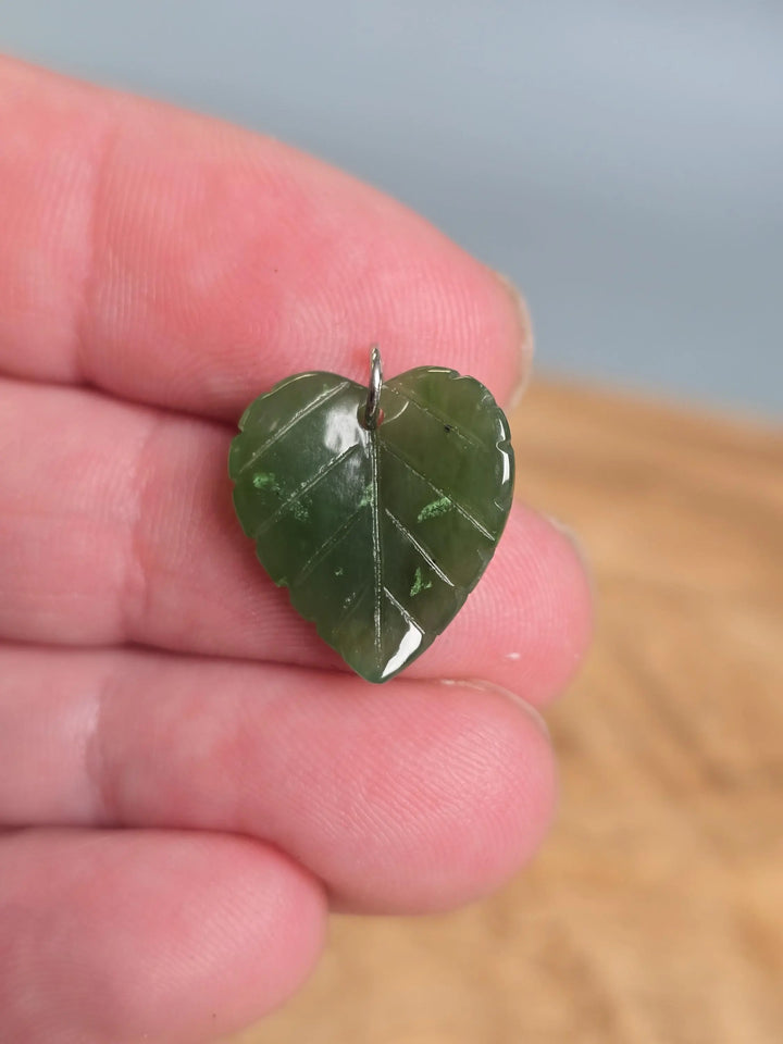 Canadian Jade leaf charm pendant with metal loop held between fingers