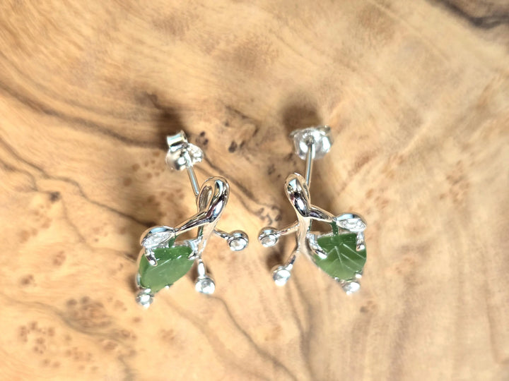 Canadian Jade Leaf and Silver Earrings shown from the front with green jade leaf and silver vine setting on a wood display